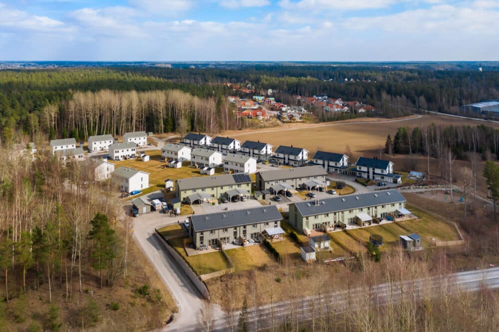 En luftbild av ett radhusområde med gröna, gråa och vita radhus