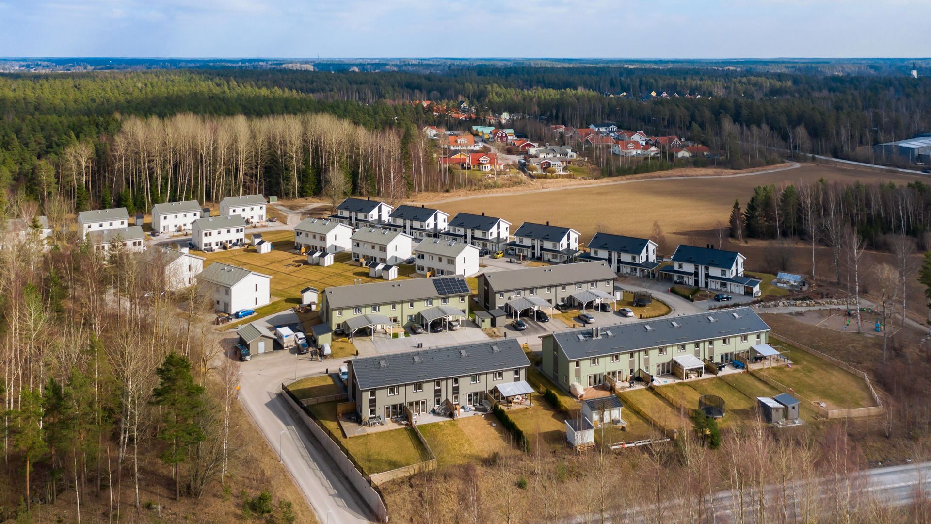 En luftbild av ett radhusområde med gröna, gråa och vita radhus